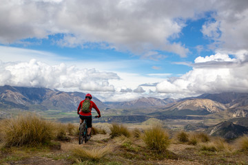 A mountain biker rides along the ridge and descends with beautiful landscape below