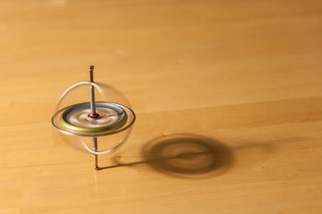 Toy gyroscope spinning and balancing on a wooden table