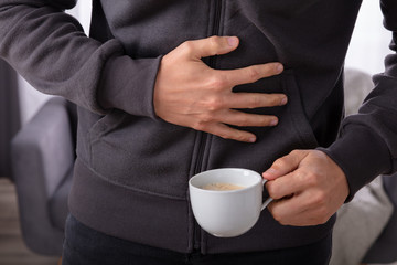 Cup Of Coffee In Front Of Man Having Stomach Pain