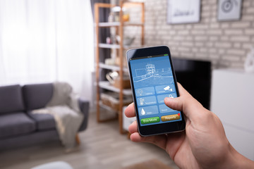 Man Using Smart Home Application On Mobile Phone