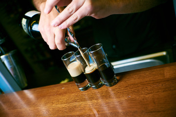 bartender hands pouring a cocktail into small cups