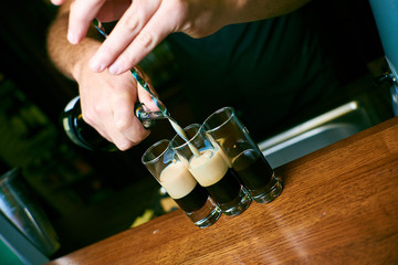 bartender hands pouring a cocktail into small cups