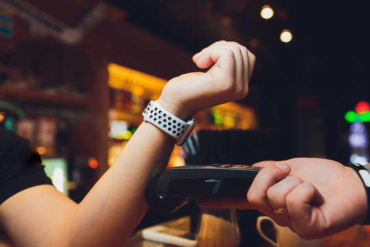 Cropped image of female customer paying through smart watch at bar.