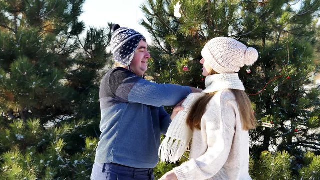 Funny man fully covers his girlfriend in scraf. Walking in winter park. 