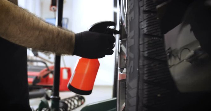A professional worker in a service station checks (pumps) the pressure of the wheels of a car. Concepts from: Car, Pressure Sensor, Tech Service.