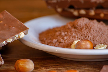 Cocoa, hazelnut and chocolate with hazelnut on wooden table. Close-up photo with vintage background.