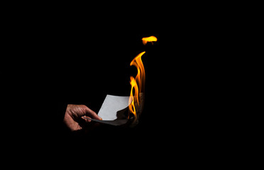 Burning sheet of paper in the male hand.