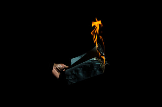 Burning sheet of paper in the male hand.