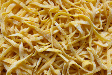 (selective focus) Fresh pasta called 'Fettuccine' made from fresh eggs and durum wheat flour. Fettuccine is a flat thick pasta popular in Roman and Tuscan cuisine.
