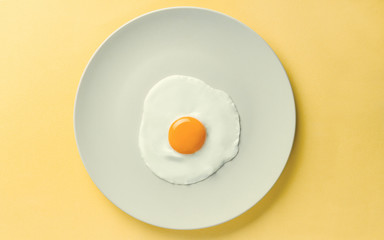 Fried egg tray on yellow background - Simple composition of egg on plate