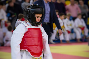 A boy in a kimono karate competition is crying because he lost the fight and was injured