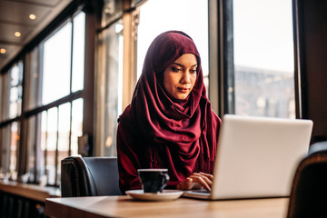 Businesswoman in hijab working from a coffee shop - Powered by Adobe