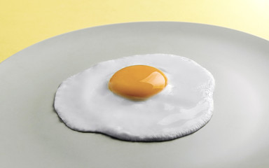 Fried egg on round plate on yellow background