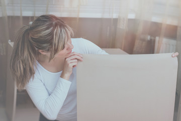 The girl looks down while standing with a sheet of paper or choose wallpaper