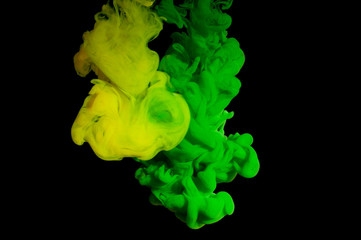 Spill and mix green and yellow paint in water on a black background