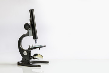 A microscope with some substance on its working surface is standing on the flat white area.