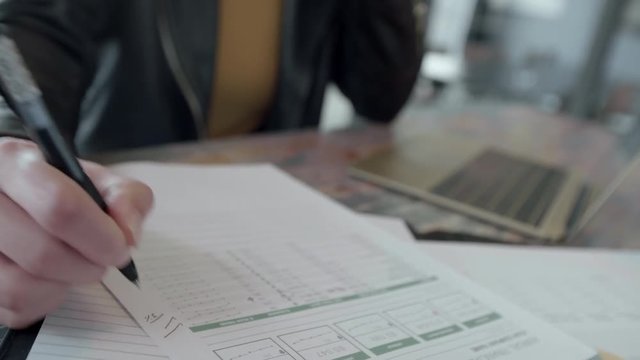 Woman working in office sitting at table doing sone paperwork. Business woman checks the financial report in office.