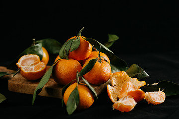 Ripe tangerines with leaves on a black background