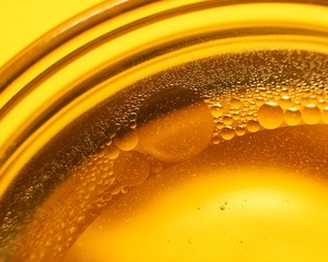 Yellow oil bubbles on water, cooking oil background.
