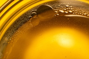 Yellow oil bubbles on water, cooking oil background.