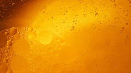 Yellow oil bubbles on water, cooking oil background.