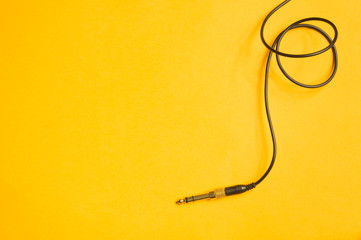 Audio jack with black cable isolated on yellow background