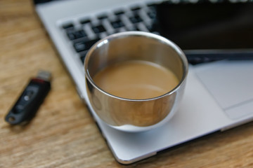 Coffee on modern laptop - ultrabook on wooden table with flash disk and external hard drive