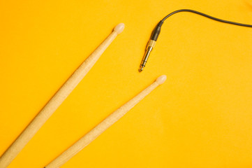 Used drumsticks and audio jack isolated on yellow background. copy space