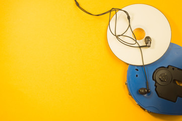 Cd player and compact disc with earphones on yellow background. copy space