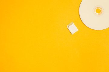 Memory card and digital disc isolated on yellow background. sd card and cd macro. copy space