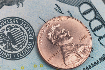 Macro photo of one cent and 100 US dollars on the background. Obverse american coin 2016 face value 1 cent photographed very close.