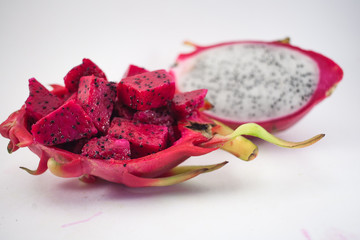 Exotic ripe pink and white Pitaya or Dragon fruit. Red Pitahaya tropical fruit cut in half and cubes on white background