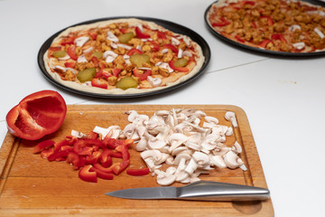 Preparation of a delicious pizza in a home kitchen. Laying and decorating pizza dough on the kitchen table.