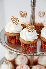 Cupcakes decorated with gingebread hearts in a two tier stand.