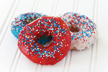 Donuts decorated with icing and sprinkles for fourth of July celebration. Selective focus with very little depth of field.