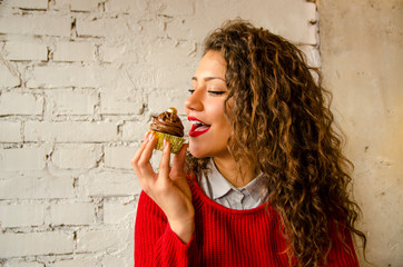 Gorgeous curly hair woman preparing to bite chocolate cupcake