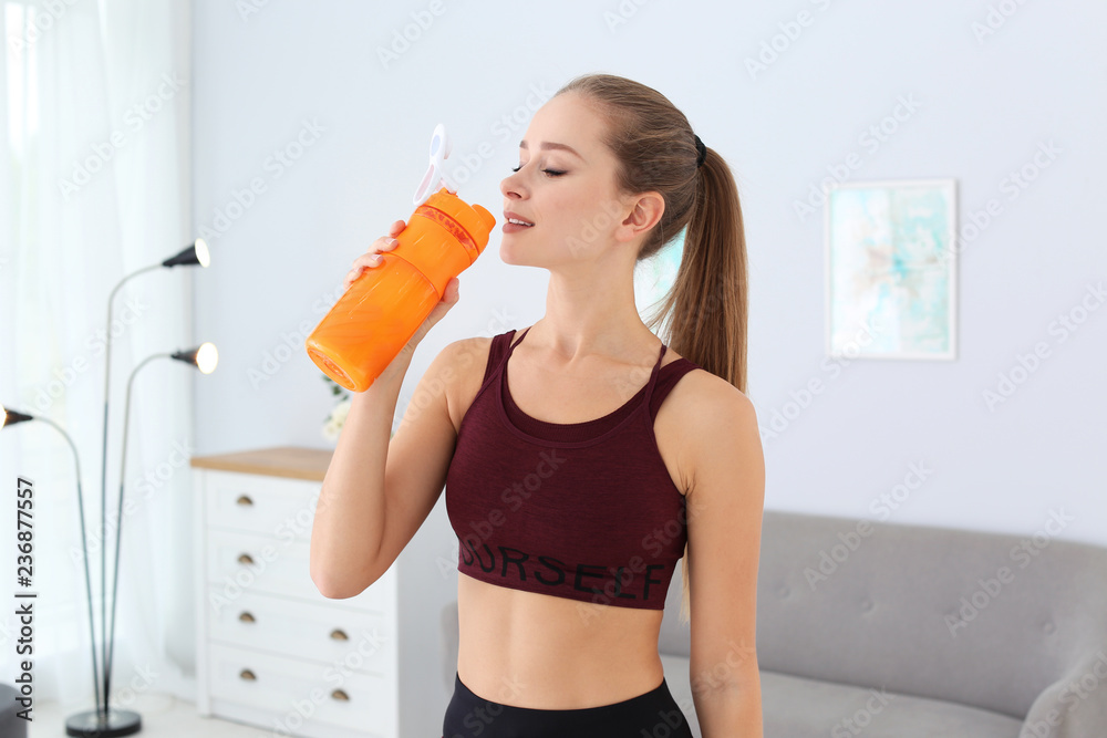 Wall mural woman drinking protein shake in living room