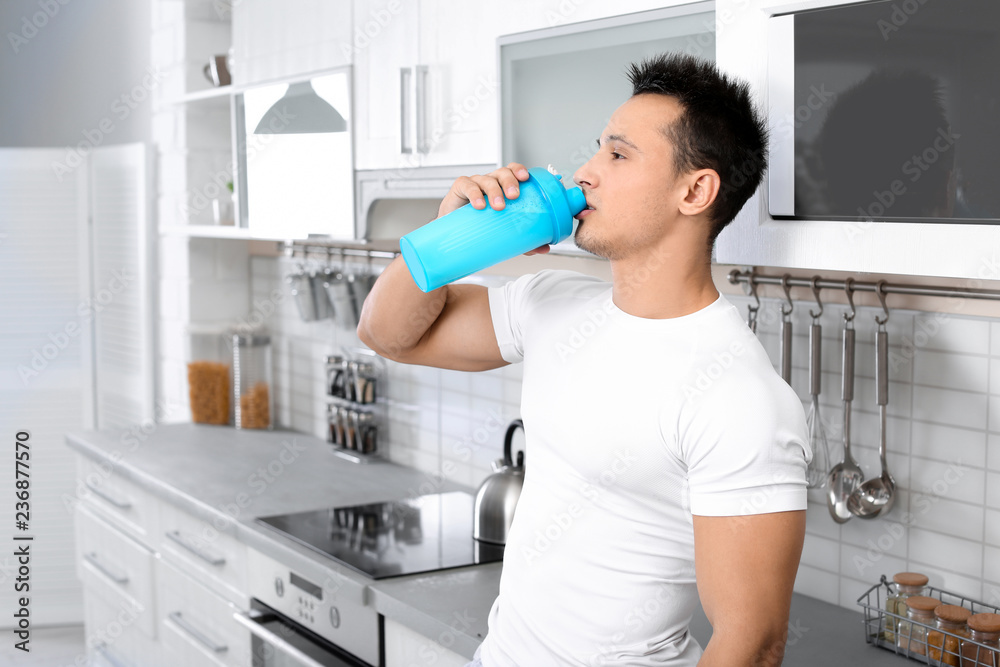 Poster Young man drinking protein shake in kitchen