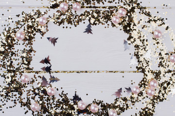 Gold glittery dots frame for Christmas holiday. New Year frame on white wooden background with copy space. Winter holiday greeting card.