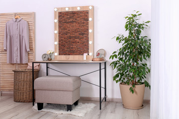 Stylish room interior with dressing table and potted ficus