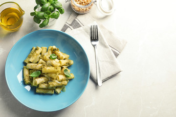 Flat lay composition with plate of delicious basil pesto pasta and space for text on gray table