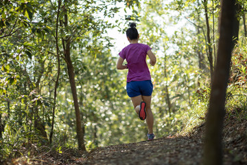 Woman trail runner running in forest mountain