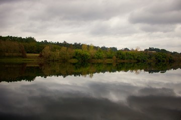 Vista do Rio Minho espelhado com reflexo da outra margem, num dia de outono.