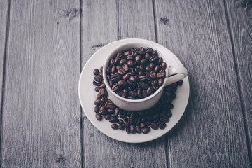 Roasted premium coffee bean in a white cup on black  and wooden background.