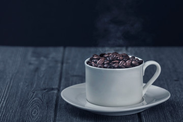 Roasted premium coffee bean in a white cup on black  and wooden background.