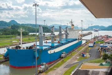 Fotobehang Kanaal Grote vrachtschepen passeren de sluizen van het Panamakanaal. Dit alledaagse evenement zorgt voor inkomsten uit zowel vergoedingen als toerisme voor het hele land.