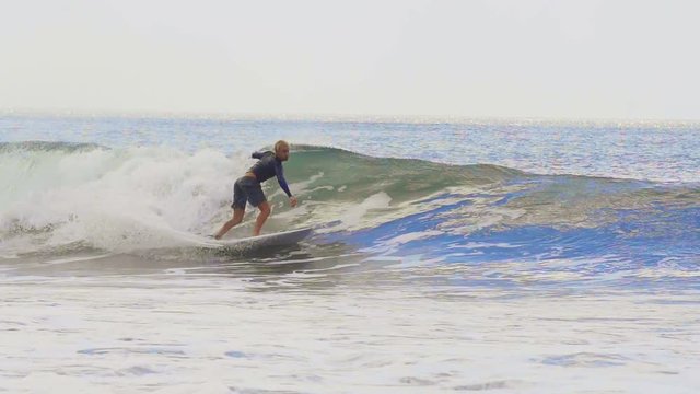 A surfer with a blonde hair is doing tricks on a wave in Nicaragua