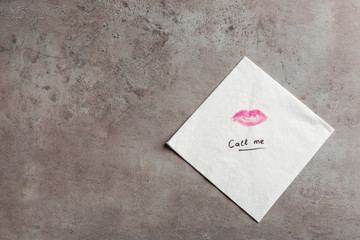 Paper napkin with lipstick mark, words CALL ME and space for text on grey background, top view