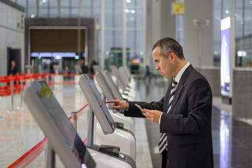 Business man at the airport check in ticket at kiosk terminal