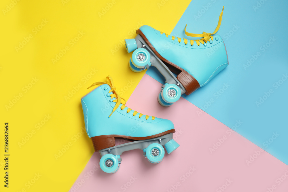 Wall mural Pair of stylish quad roller skates on color background, top view